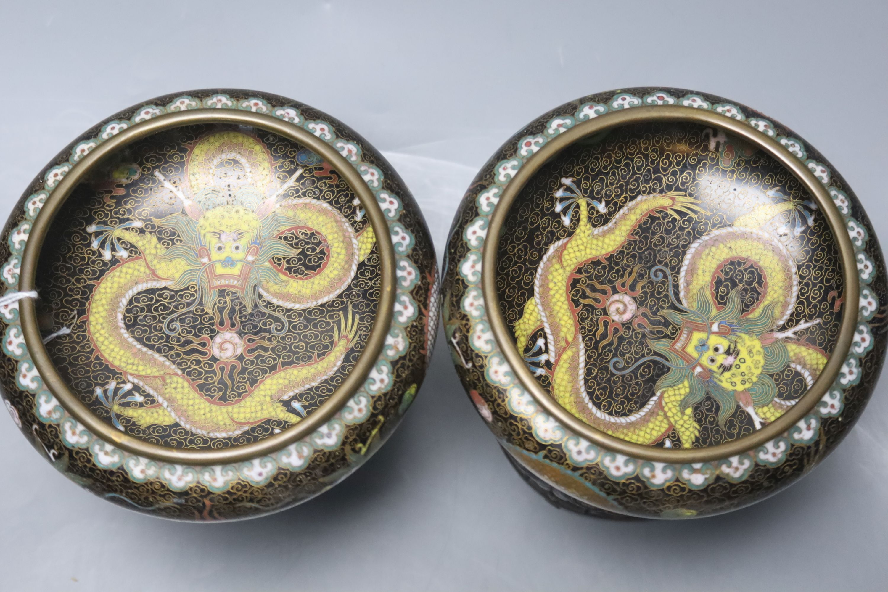 A pair of Chinese cloisonne enamel small 'dragon' bowls, wood stands